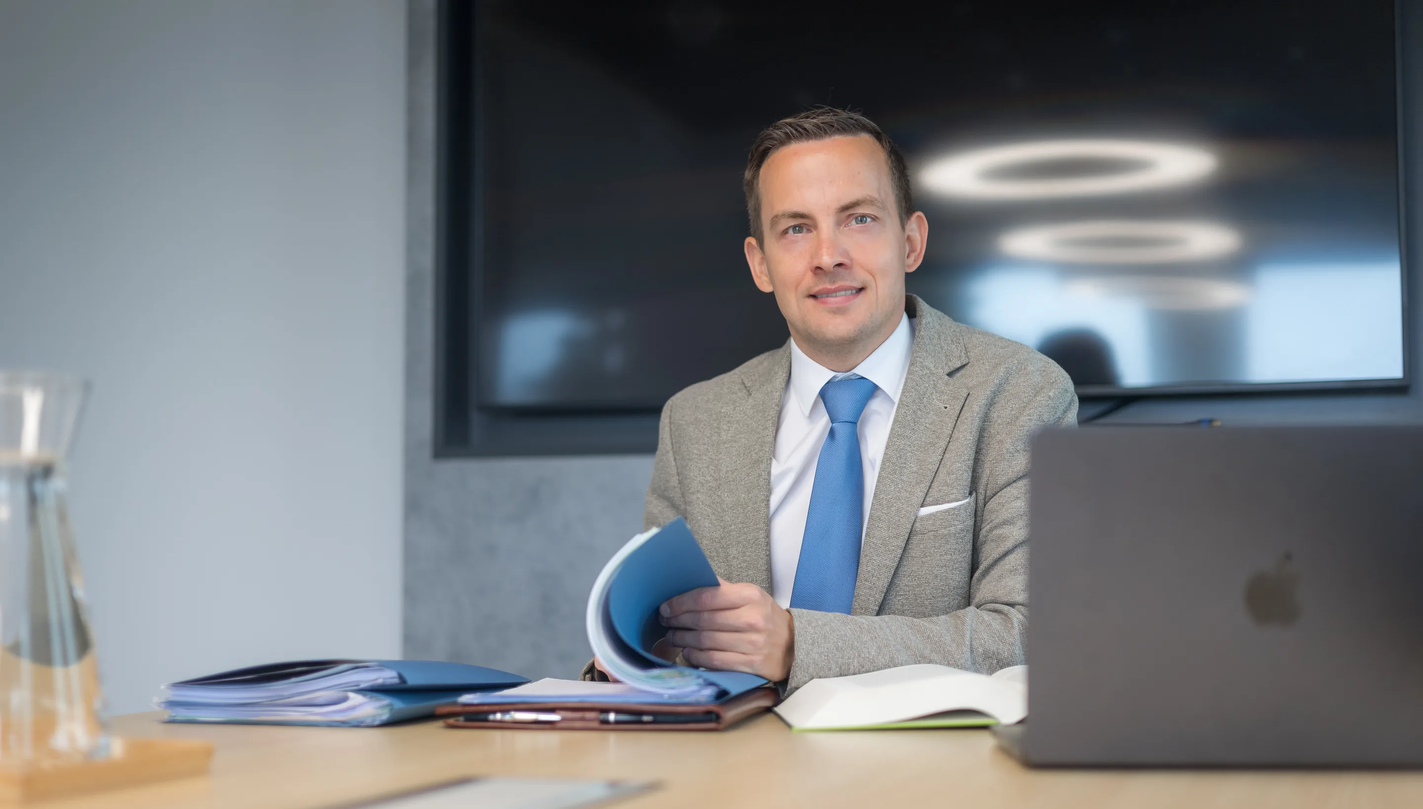 Dr. Daniel Holzinger mit einer Mappe am Besprechungstisch